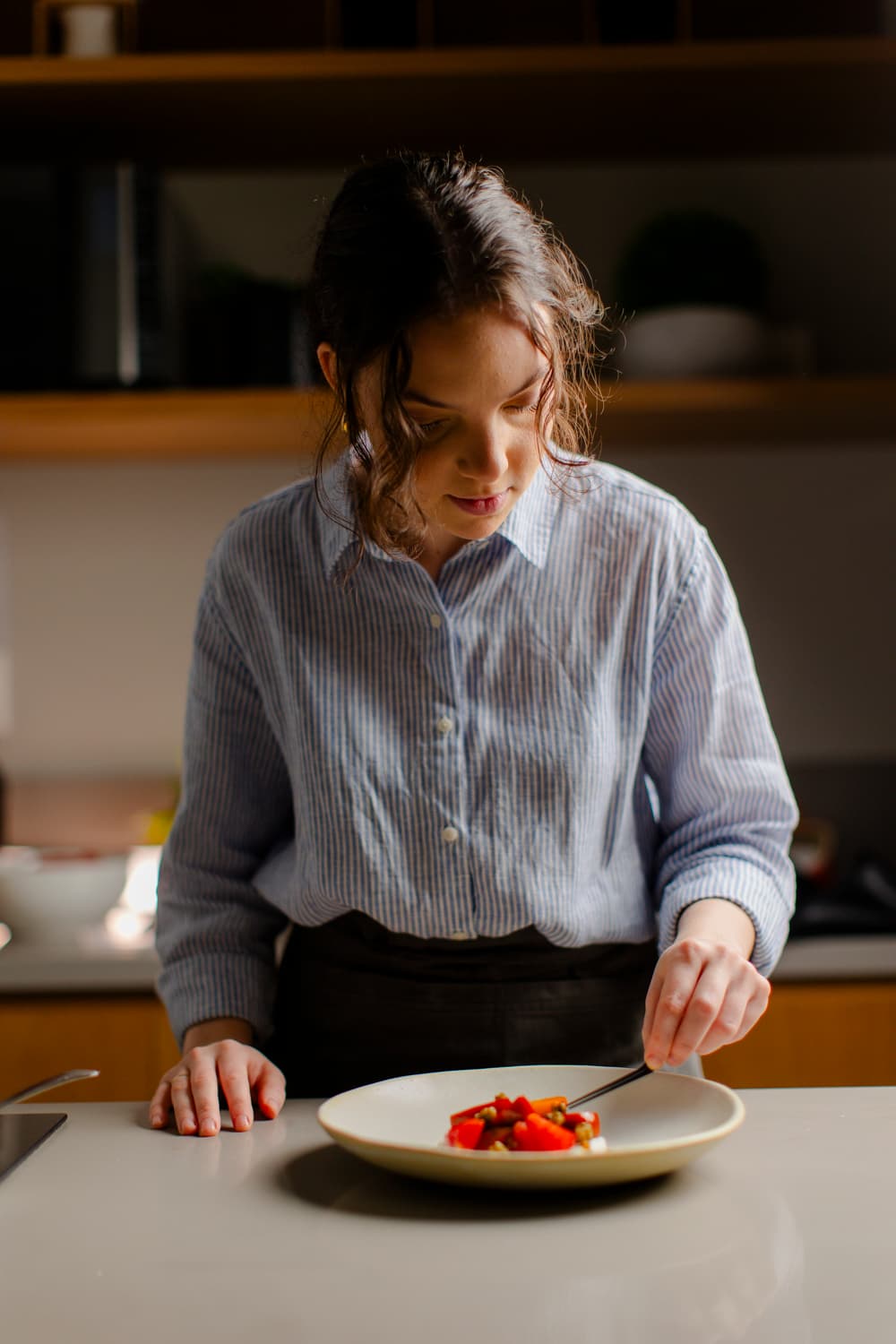 Alexia finalizando um prato com tomates na cozinha